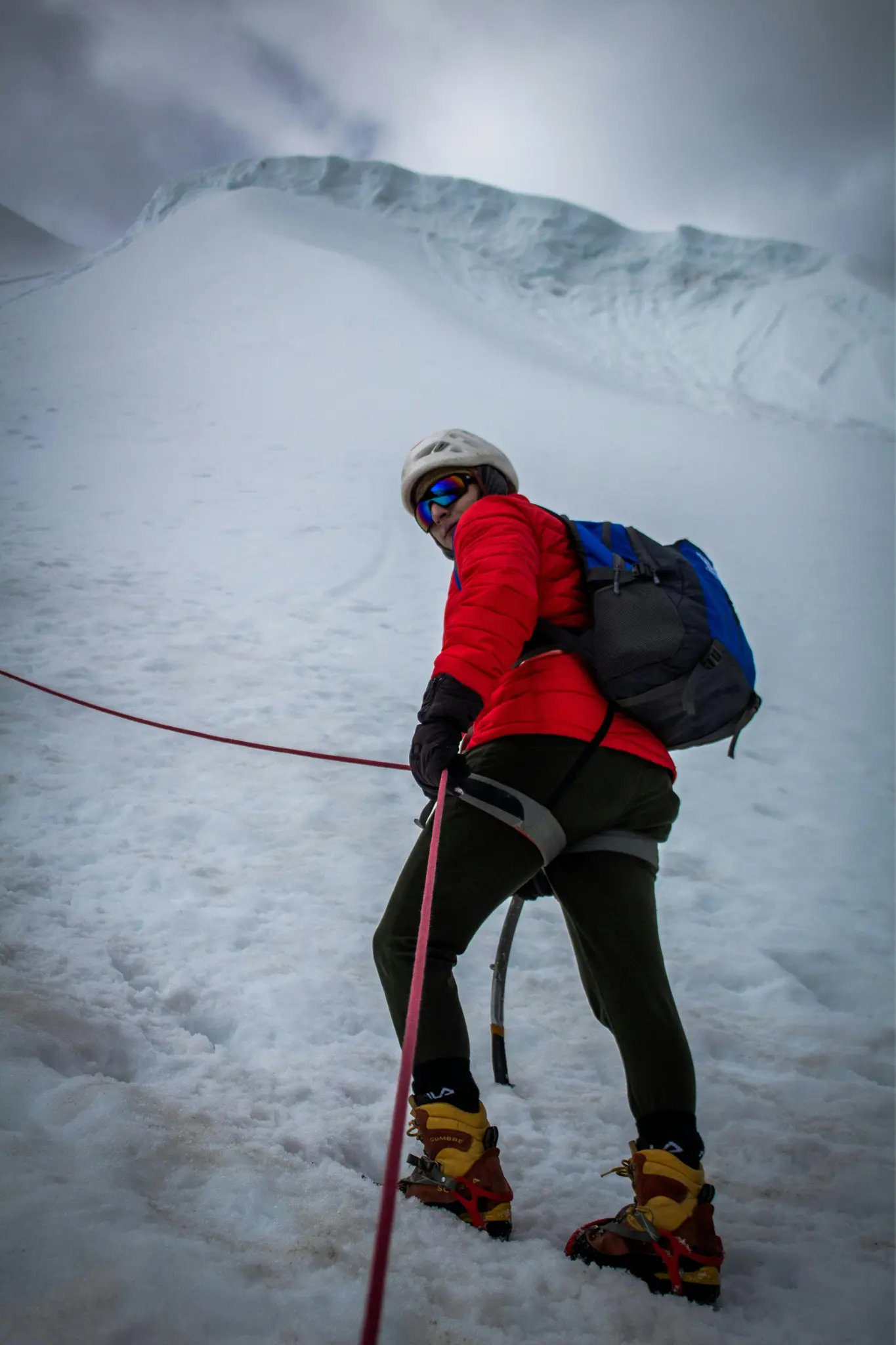 Male mountaineer looking back while ascending a snow-covered mountain.